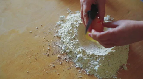 Hand to breaking an egg in flour,salt, and  mixing flour and egg on table Vídeo Stock 58874301