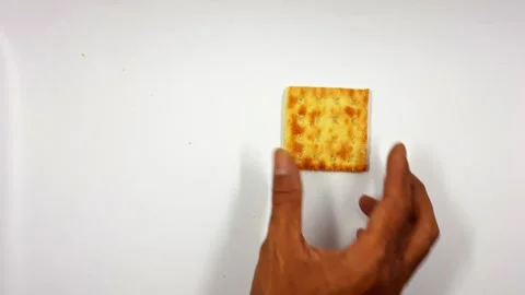 Hand breaking a golden square cracker into two halves, video motion Stock Footage 331791542
