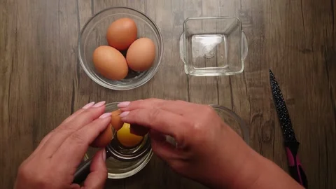 The hand breaks the egg and separates the yolk from the protein Stock Footage 240396981