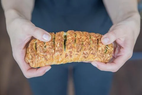 A hand breaks a spinach bun in half close-up. Eating quick snacks. Stock Photos