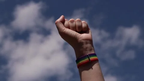 Hand with bright pride strap against cloudy sky on sunny day Stock Footage 340402630