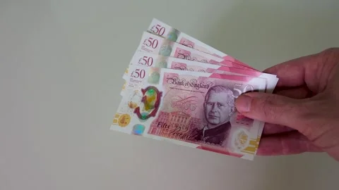 Hand brings £200 in £50 notes into frame and holds them in centre, slow motion Stock Footage 334231350