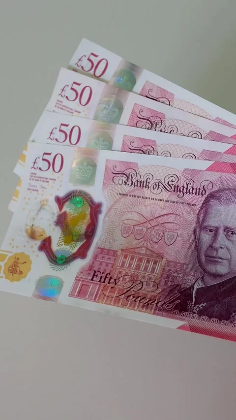 Hand brings £200 in £50 notes into frame and holds them in centre, slow motion Stock Footage 334241610