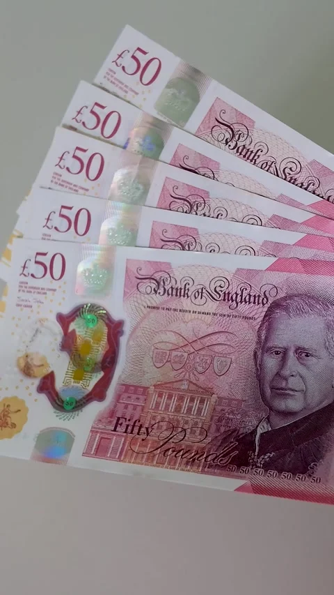 Hand brings five £50 notes totalling £250 into centre frame, slow motion Stock Footage 334241973