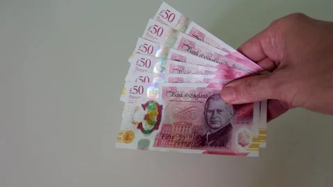 Hand brings six £50 notes totalling £300 into centre frame, slow motion Stock Footage 334231249