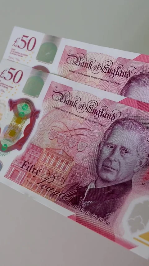 Hand brings two £50 notes into centre frame and holds them, slow motion Stock Footage 334242507