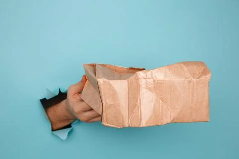 Hand with a broken delivery box through a paper hole. Shipment's accident Stock Photos
