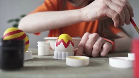 Hand with a brush is drawing a colored pattern on an Easter egg. Stock Footage 176860514