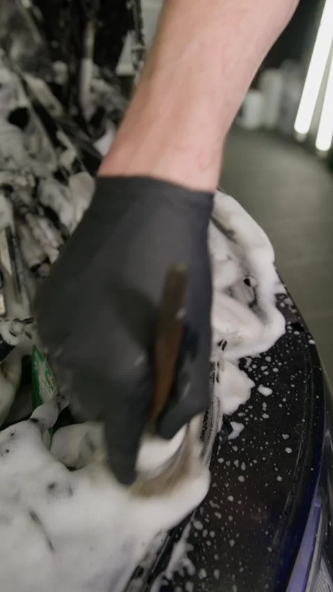 A hand with a brush washes and cleans the engine elements under the hood of the Video stock 289779664