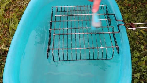 A hand with a brush washes the grill grate slowly in a blue basin. FullHD Vídeos de archivo 140916037