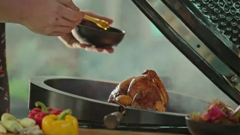Hand brushing roasted whole chicken on a the grill bbq barbeque kamado camado Stock Footage 292808802