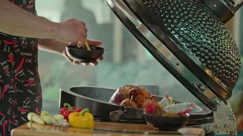 Hand brushing roasted whole chicken on a the grill bbq barbeque kamado camado Stock Footage 292809307