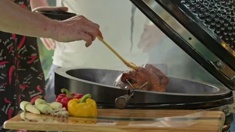 Hand brushing roasted whole chicken on a the grill bbq barbeque kamado camado Stock Footage 292810200