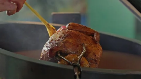 Hand brushing roasted whole chicken on a the grill bbq barbeque kamado camado Stock Footage 292810592