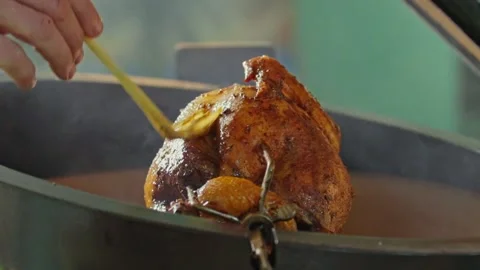 Hand brushing roasted whole chicken on a the grill bbq barbeque kamado camado Stock Footage 292811294