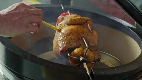 Hand brushing roasted whole chicken on a the grill bbq barbeque kamado camado Video stock 292812324
