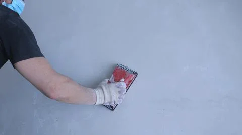 Hand of a builder with an emery device on a wall background Stock Photos