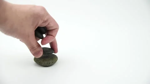 Hand building pyramids of gray zen pebble hot stones on white background Stock Footage 143777880