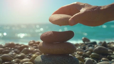 Hand building stones pyramid on pebble beach, stability, zen, harmony, balance Stock Footage 116547572