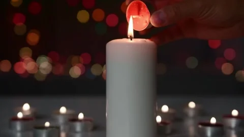Hand burning a small candle from the bright flame of a large warm candle. Stock Footage 148138990