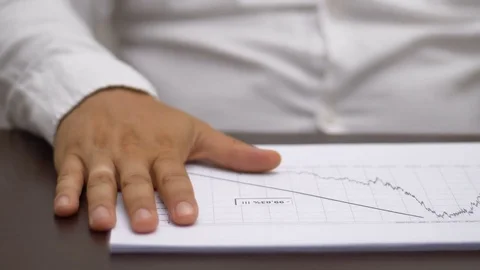 Hand of business manager beating on negative economic data's paper Stock Footage 78248617