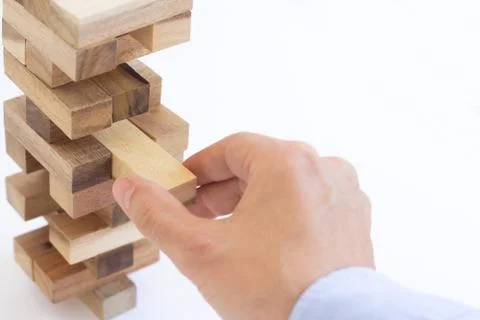 Hand of businessman pulling out or placing wood block on the tower Stock Photos