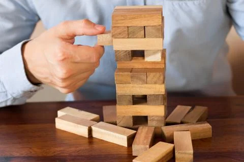 Hand of businessman pulling out or placing wood block on tower Stock Photos
