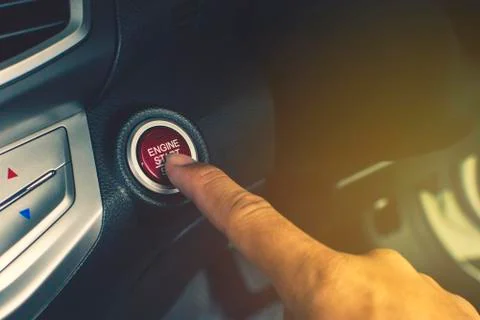 Hand of car driver press to the engine start/stop button. Stock Photos