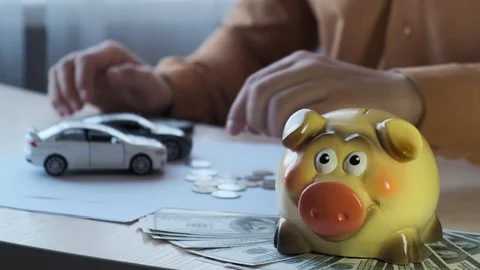 Hand of an car insurance agent throwing a coin into a piggy bank Stock Footage 118375654