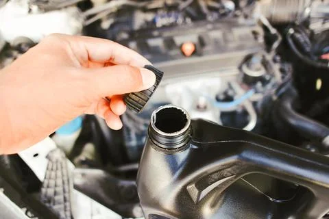The hand of a car mechanic opens the engine oil cap to inspect Stock Photos