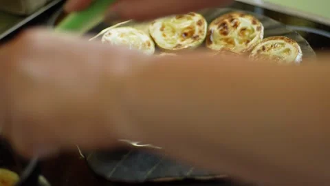 Hand carefully adds a slice of green zucchini to a heated frying pan, while a Stock Footage 280916278