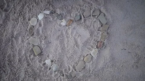 A hand carefully arranges small stones to form heart on smooth surface Each Vidéo 282904983