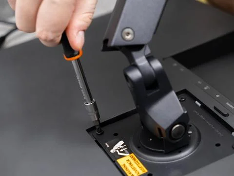 Hand carefully attaching a computer display to an adjustable desk mount usi.. Stock Photos
