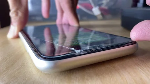 Hand carefully pulling screen protection glass from cracked phone display Stock Footage 255890768
