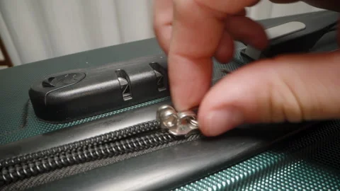 A Hand carefully removes the zipper pull from the suitcase's combination lock, Stock Footage 282312902