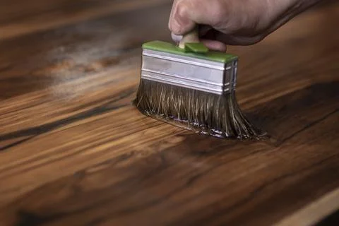 Hand of a carpenter designer oiling an authentic self made table with a brush 스톡 사진