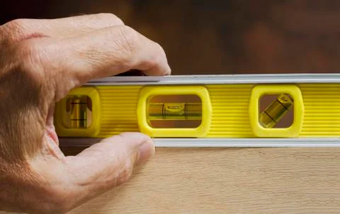 Hand on carpenter level Stock Photos