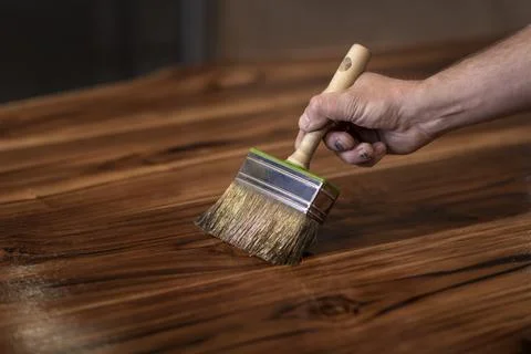 Hand of a carpenter oiling an authentic self made table with a big brush Fotos de archivo