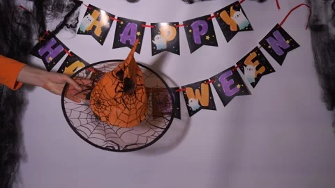 The hand carries an orange witch hat with a pattern on the background of the Stock Footage 254613124