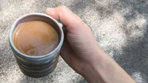 Hand carrying a coffee mug while walking outside Stock Footage 91542769