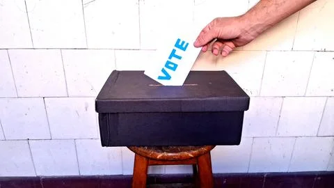 Hand casting blue vote paper into a simple black box Stock Photos