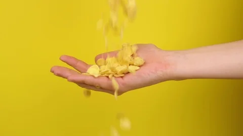 Hand catches cornflakes on yellow background Stock Footage 125820520