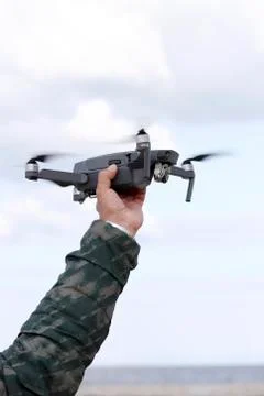 Hand catching drone in sky background Stock Photos