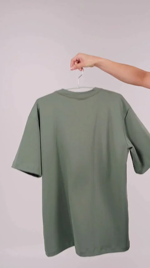 Hand catching folded green tshirt on metal clothes hanger Stock Footage 331774030