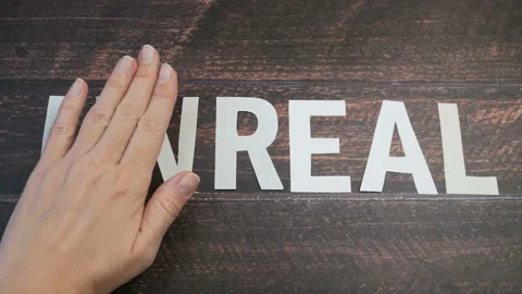 Hand changes the word unreal to real on wooden background. closeup Stock Footage 144370991