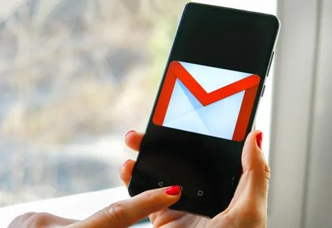 Hand check emails Gmail app by Google on smartphone Stock Photos