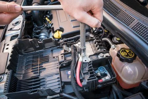 Hand checking the bolt of a car battery with a wrench Stock Photos
