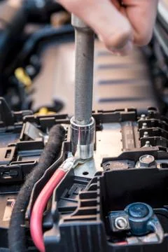 Hand checking the bolt of a car battery with a wrench Stock Photos