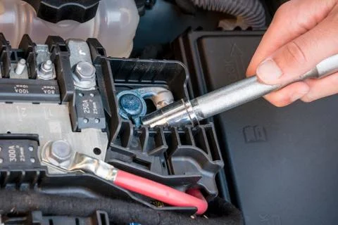 Hand checking the bolt of a car battery with a wrench Stock Photos