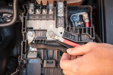 Hand checking the cables of a car battery Stock Photos
